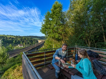 Zwei Personen machen Picknick auf der Aussichtsplattform mit Blick auf das Viadukt in Altenbeken