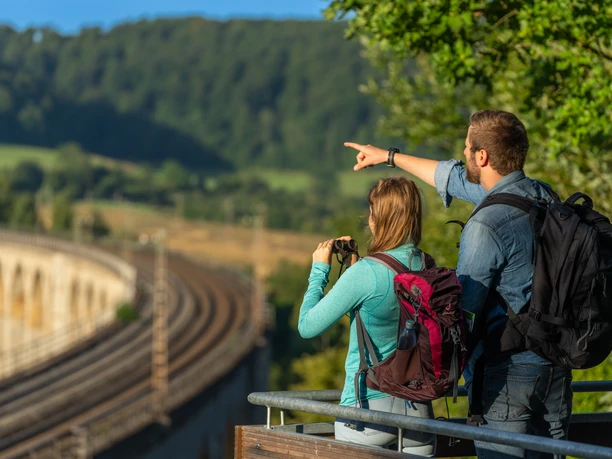 Ein Mann und eine Frau schauen mit dem Fernglas auf die Schienen des Viadukts in Altenbeken