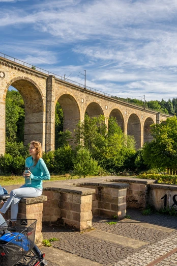 Ein Mann und eine Frau machen Pause auf ihrer Fahrradtour vor dem Viadukt Altenbeken