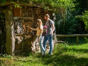 Zwei Personen auf Wanderung vor dem Insektenhotel am Waldhaus Altenbeken