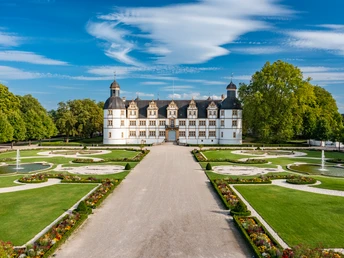 Schloss Neuhaus bei Paderborn mit barockem Garten, symmetrischen Beeten und Springbrunnen im Sommer.