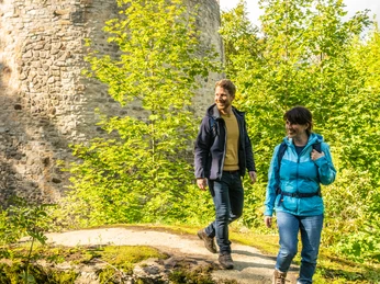 Bad Driburg-Iburg-Teutoburger-Wald-Tourismus-D-Ketz-063.jpg Ein Mann und eine Frau mit Rucksack lächelnd vor der Iburg in Bad Driburg