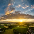 Rahden-Teutoburger-Wald-Tourismus-D-Ketz-001.jpg Ein atemberaubender Sonnenuntergang über einer weiten, grünen Landschaft mit vereinzelten Wolken am Himmel.