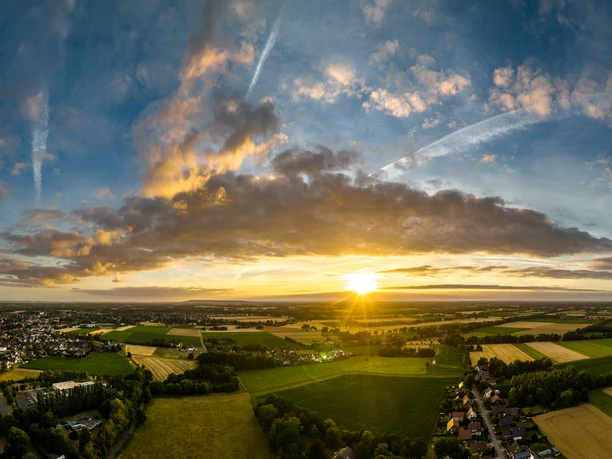 Rahden-Teutoburger-Wald-Tourismus-D-Ketz-001.jpg Ein atemberaubender Sonnenuntergang über einer weiten, grünen Landschaft mit vereinzelten Wolken am Himmel.