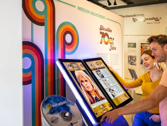 Espelkamp-Schloss Benkhausen-Automatenmuseum-Teutoburger-Wald-Tourismus-D-Ketz-074.jpg Museumsbesucher interagieren mit einem digitalen Bildschirm, das das Wirken von Musikikonen zeigt.