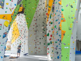 YOYO Kletterhalle Kletterhalle mit bunten Kletterwänden; eine Person klettert, während eine andere sichert. Helle, lebendige Atmosphäre.Climbing hall with colorful climbing walls; one person climbs while another belays. Bright, lively atmosphere.Lezecká hala s barevnými lezeckými stěnami; jedna osoba leze, zatímco druhá jistí. Jasná, živá atmosféra.Hala wspinaczkowa z kolorowymi ściankami wspinaczkowymi; jedna osoba wspina się, a druga asekuruje. Jasna, żywa atmosfera.Klimhal met kleurrijke klimwanden; één persoon klimt terwijl een ander begeleidt. Heldere, levendige sfeer.Palestra di arrampicata con pareti colorate; una persona si arrampica mentre un'altra assicura. Atmosfera luminosa e vivace.