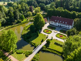 Luftaufnahme eines historischen Herrenhauses mit weitläufigem Garten und Wassergräben in Preußisch Oldendorf.