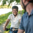 Preußisch Oldendorf-Mittellandkanal-Teutoburger-Wald-Tourismus-D-Ketz-094.jpg Zwei Radfahrer mit Helmen lächeln auf einem grünen Weg, der von Bäumen gesäumt ist, zueinander.