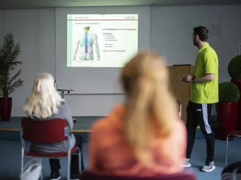 Rückenschule MEDICLIN Rose Klinik Teilnehmer einer Rückenschulungsveranstaltung betrachten eine Präsentation über die Wirbelsäule.