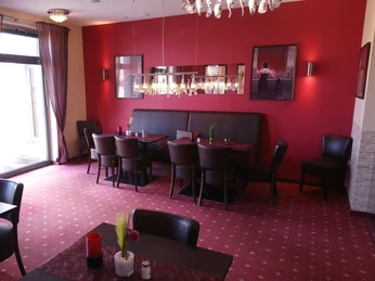 DSC_1971.JPG Ein eleganter Essbereich mit roten Wänden, hölzernen Tischen und Stühlen, dekoriert mit Kronleuchtern.