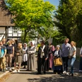 Stemwede-Stiftsort Levern-Teutoburger-Wald-Tourismus-D-Ketz-051.jpg Eine Gruppe Menschen in historischer Kleidung steht in einem sonnigen Dorf vor Fachwerkhäusern.