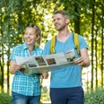 Stemwede-Waldlehrpfad Stemweder Berg-Teutoburger-Wald-Tourismus-D-Ketz-035.jpg Zwei fröhliche Wanderer mit Karte auf einem bewaldeten Lehrpfad im Sonnenlicht.