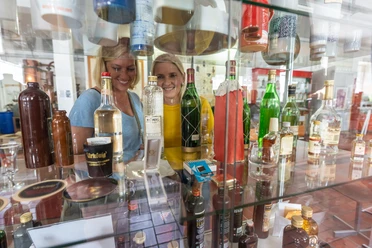 Zwei Frauen betrachten Flaschen in einem Regal, umgeben von verschiedenen Spirituosen in einer Ausstellung.