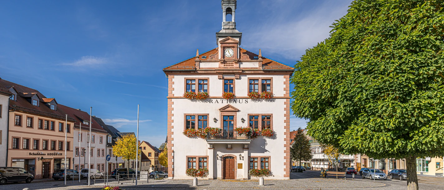 La photo montre la mairie de Geithain derrière le grand marché pavé, les fenêtres sont toujours décorées de riches jardinières.