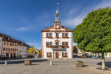 Rathaus am Marktplatz in Geithain Das Bild zeigt das Geithainer Rathaus hinter dem großen gepflasterten Markt, Die fenster sind immer mit reichen Blumenkästen geschmückt.