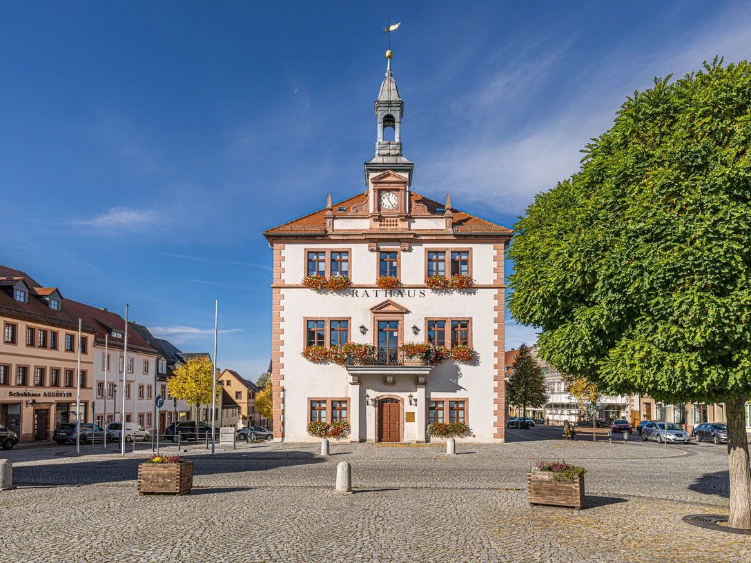Rathaus am Marktplatz in Geithain Das Bild zeigt das Geithainer Rathaus hinter dem großen gepflasterten Markt, Die fenster sind immer mit reichen Blumenkästen geschmückt.