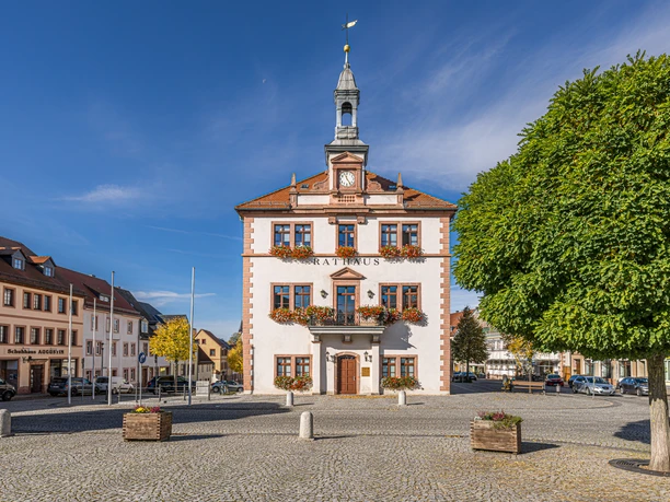 Rathaus am Marktplatz in Geithain Das Bild zeigt das Geithainer Rathaus hinter dem großen gepflasterten Markt, Die fenster sind immer mit reichen Blumenkästen geschmückt.