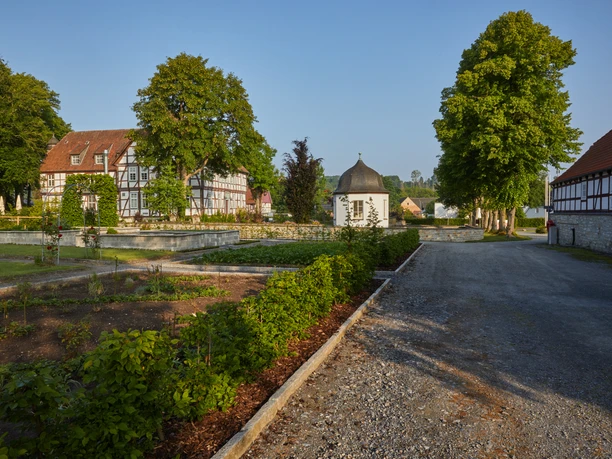 Hofgut mit historischen Fachwerkgebäuden und gepflegten Gärten in Borchen bei sonnigem Wetter.