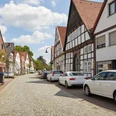 Eine charmante Kopfsteinpflasterstraße mit nichtidentifizierten Autos und malerischen Fachwerkhäusern.