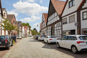 Salzkotten-Fachwerk-Teutoburger-Wald-Tourismus-T-Evers-015.jpg Eine charmante Kopfsteinpflasterstraße mit nichtidentifizierten Autos und malerischen Fachwerkhäusern.