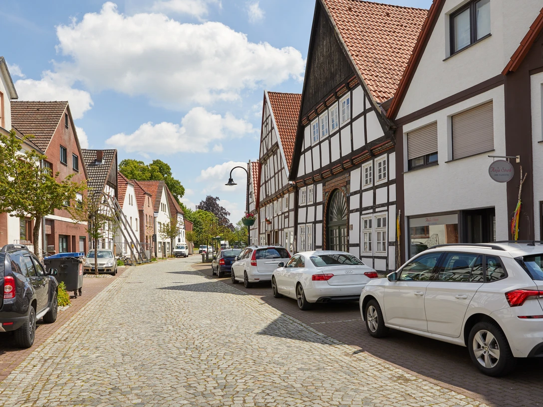 Salzkotten-Fachwerk-Teutoburger-Wald-Tourismus-T-Evers-015.jpg Eine charmante Kopfsteinpflasterstraße mit nichtidentifizierten Autos und malerischen Fachwerkhäusern.