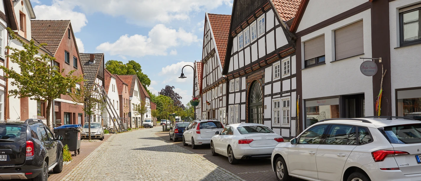 Salzkotten-Fachwerk-Teutoburger-Wald-Tourismus-T-Evers-015.jpg Eine charmante Kopfsteinpflasterstraße mit nichtidentifizierten Autos und malerischen Fachwerkhäusern.