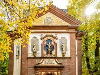 Lichtenau-Kirche Maria Heimsuchung-Teutoburger-Wald-Tourismus-D-Ketz-058-CC-BY-SA.jpg Barockkirche mit verzierten Fassaden, herbstlichen Bäumen und strahlender Sonne im Hintergrund.