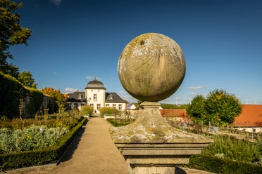 Lichtenau-Kloster Dalheim-Teutoburger-Wald-Tourismus-D-Ketz-070-CC-BY-SA.jpg Eine historische Sonnenuhr aus Stein in einem gepflegten Schlossgarten vor einem barocken Gebäude.