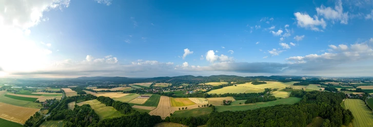 Lage-Hoerster Egge-Teutoburger-Wald-Tourismus-D-Ketz-009.jpg Panoramablick über eine ländliche Region mit Feldern, Wäldern und kleinen Dörfern unter blauem Himmel.
