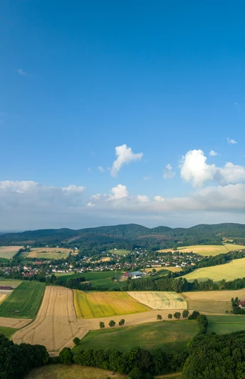 Lage-Hoerster Egge-Teutoburger-Wald-Tourismus-D-Ketz-009.jpg Panoramablick über eine ländliche Region mit Feldern, Wäldern und kleinen Dörfern unter blauem Himmel.
