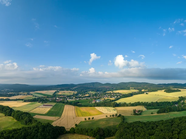 Lage-Hoerster Egge-Teutoburger-Wald-Tourismus-D-Ketz-009.jpg Panoramablick über eine ländliche Region mit Feldern, Wäldern und kleinen Dörfern unter blauem Himmel.