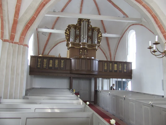 Kirche mit Orgel in Canum Innenraum der Kirche Canum mit hölzerner Orgel auf der Empore und hellgrauen Sitzbänken.