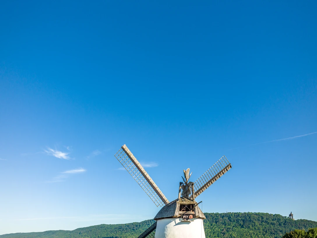Porta Westfalica-Windmühle Holzhausen-Teutoburger-Wald-Tourismus-D-Ketz-023-CC-BY-SA.jpg Historische Windmühle in Preußisch Oldendorf mit markanten Flügeln, umgeben von grüner Landschaft.