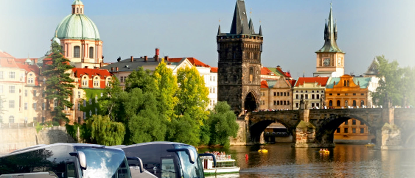 Two silver coaches in front of a historic city view with a bridge and towers, with the lettering "Reiseverkehr Puttrich GmbH" above them.