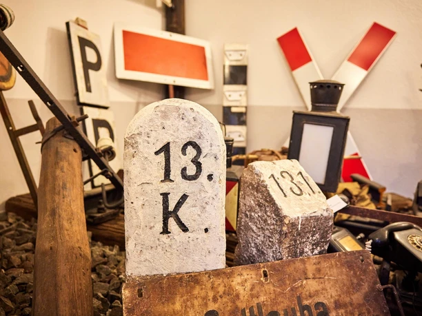 Stenen markeringen met de nummers "13. K." en "131" voor oude spoorwegborden en een zwarte telefoon in een nostalgische kamer.