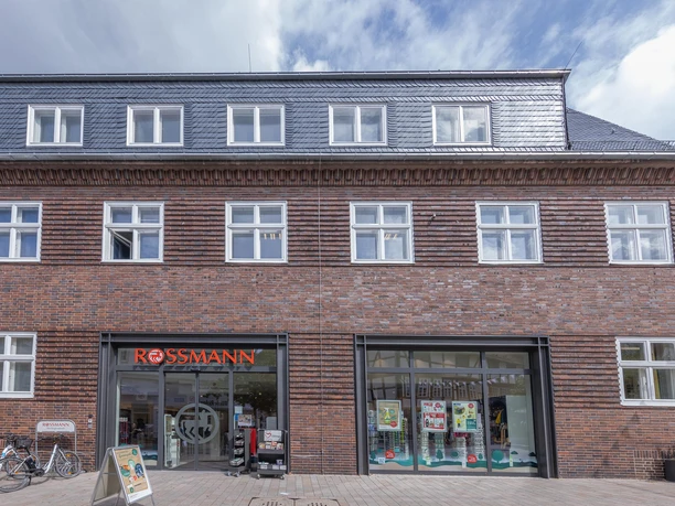 Rossmann-Filiale in einem Backsteingebäude mit Schaufenstern und Fahrrädern davor