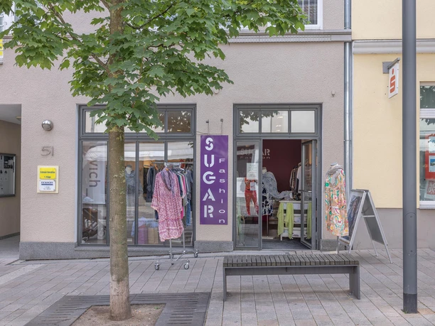 Schaufenster von Sugar Fashion mit Kleiderständern und geöffneter Ladentür