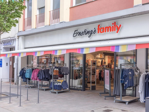 Ernsting’s-family-Filiale mit bunter Markise und Kleidung vor dem Eingang