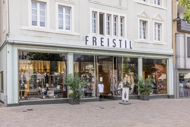 Schaufenster des Modegeschäfts Freistil mit Schaufensterpuppen und Pflanzen davor