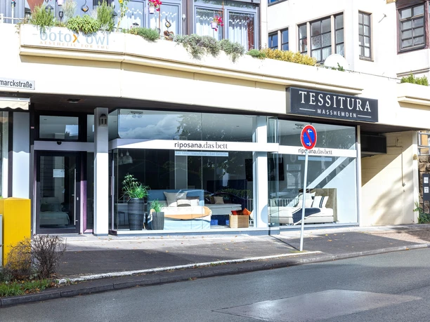 Schaufenster von riposana.das bett mit Betten und Pflanzen an einer Straße