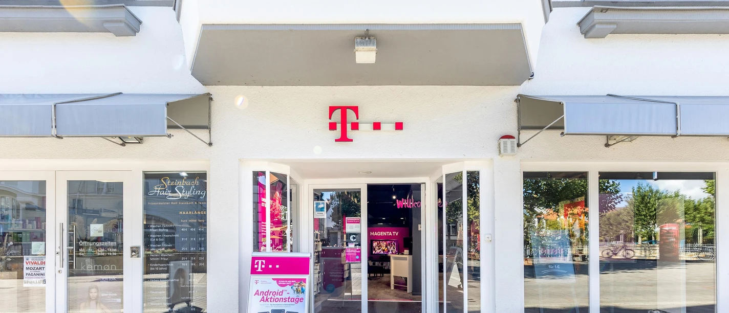 Telekom-Shop in weißer Häuserfassade mit offenem Eingang und Werbeaufsteller