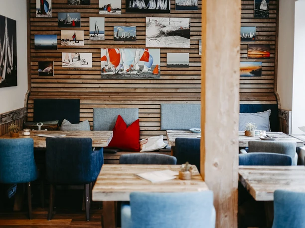 Gezellig restaurant met zeilbootmotieven op houten muren, smaakvolle stoffering en houten tafels.