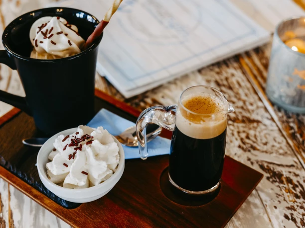 An espresso with whipped cream and another cup of coffee, atmospherically arranged on a tray.