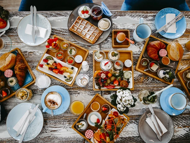 Een rijkelijk gedekte ontbijttafel met verschillende dranken en heerlijke broodjes.