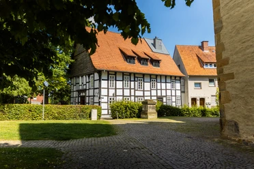 Enger-Widukind-Museum-Teutoburger-Wald-Tourismus-H-Tornow-002-CC-BY-SA.JPG Fachwerkhaus an einem sonnigen Tag, umgeben von gepflastertem Weg und einigen Bäumen im Vordergrund.