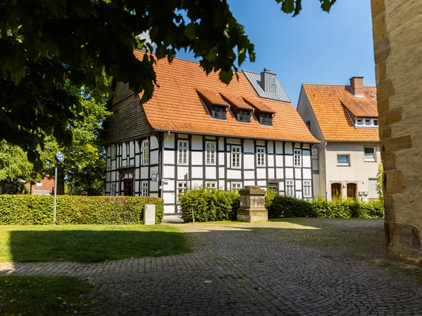 Enger-Widukind-Museum-Teutoburger-Wald-Tourismus-H-Tornow-002-CC-BY-SA.JPG Fachwerkhaus an einem sonnigen Tag, umgeben von gepflastertem Weg und einigen Bäumen im Vordergrund.