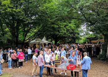 Büdchen am Westerberg .jpg Eine Menschenmenge genießt an einem sonnigen Tag ein geselliges Event im Freien, umgeben von Bäumen.