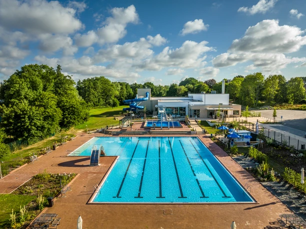 Kirchlengern-Aqua Fun-Teutoburger-Wald-Tourismus-D-Ketz-001.jpg Ein großes Freibad mit mehreren Schwimmbecken, Liegeflächen und Wasserrutsche in grüner Umgebung.