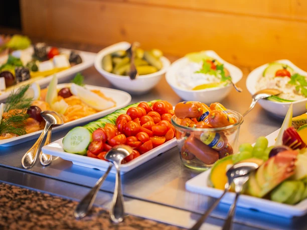 Various breakfast pastries, fresh fruit, vegetables and cold cuts are arranged on a buffet.
