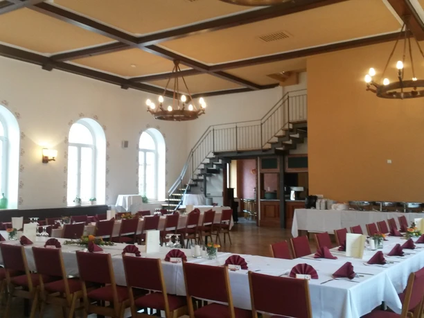 Saal im Gasthof Hillig Ein großer, gut beleuchteter Veranstaltungssaal mit stilvoll gedeckten Tischen und hoher Decke.
